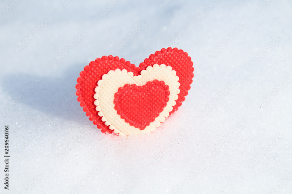 A beautiful red soft heart made of cloth in the snow. Close-up. Background. Texture. Isolated.