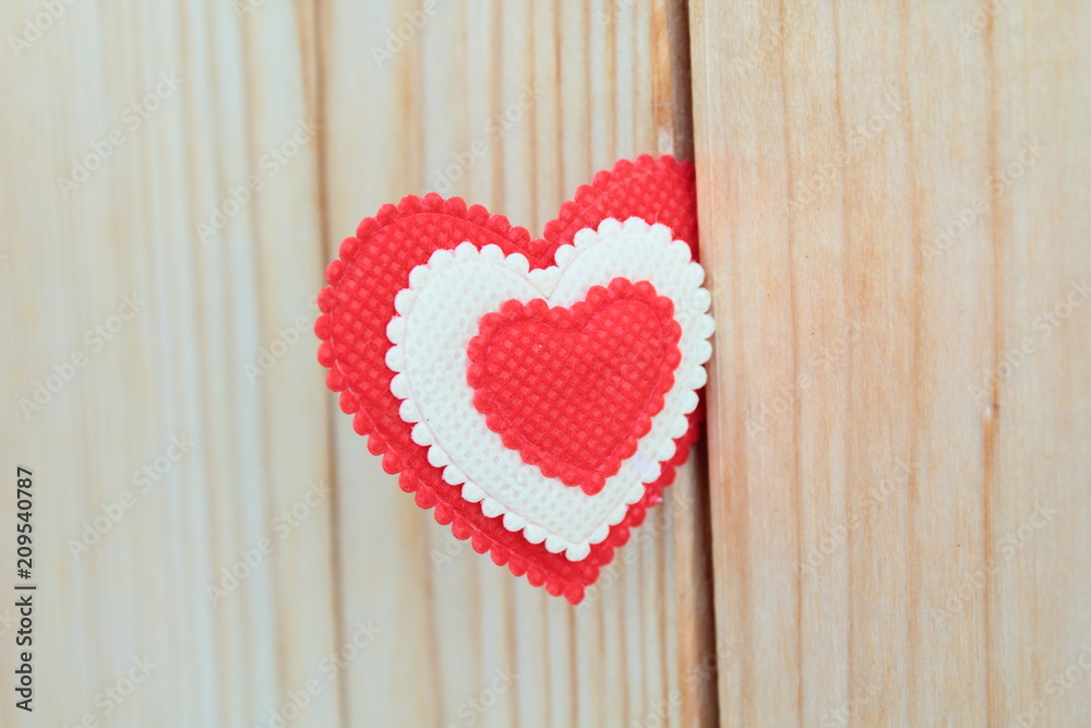 A beautiful red soft heart made of cloth on a light new board. Close-up. Background. Texture. A beautiful red soft heart made of cloth on a light new board. Close-up. Background. Texture.