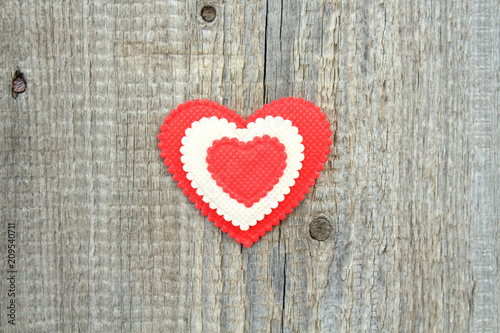 A beautiful soft heart made of cloth on an old board. Close-up. Background. Texture.