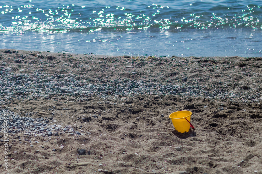 Children's toy bucket on an empty beach Children's toy bucket on an empty beach