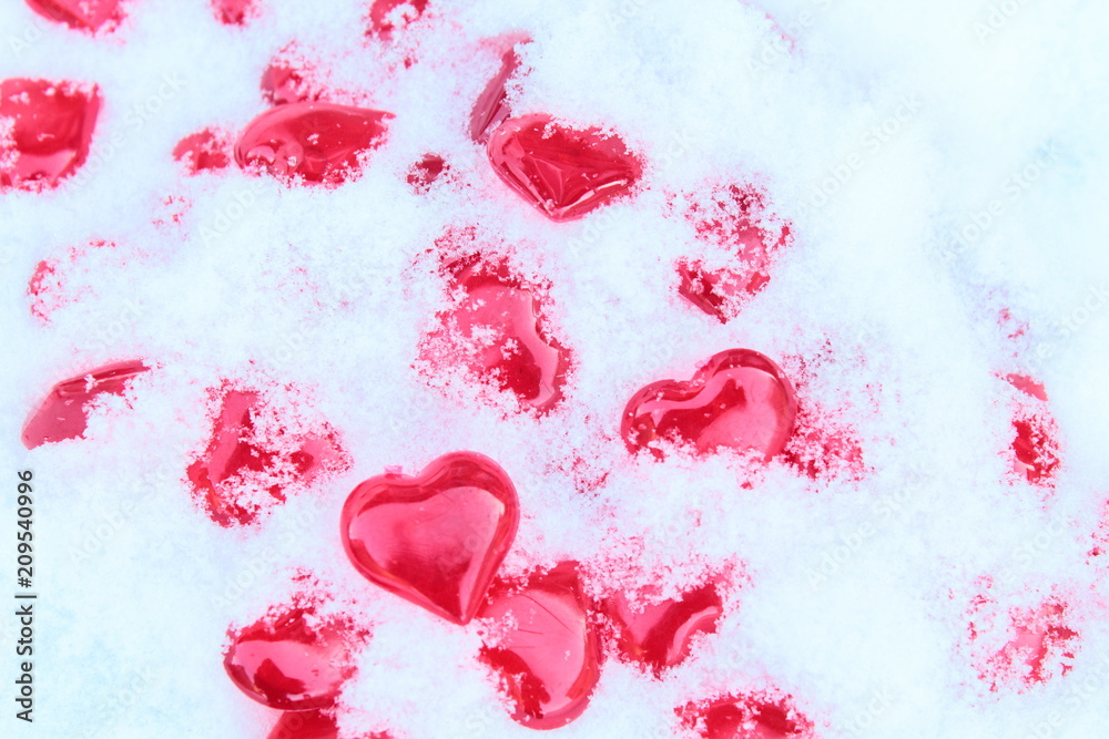 Beautiful red voluminous transparent hearts made of fiberglass in natural cold snow. Close-up. Background. Texture.