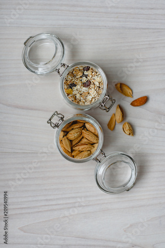 Still life of healthy food and diet food, almonds and muesli in glass jars on a wooden background. photo