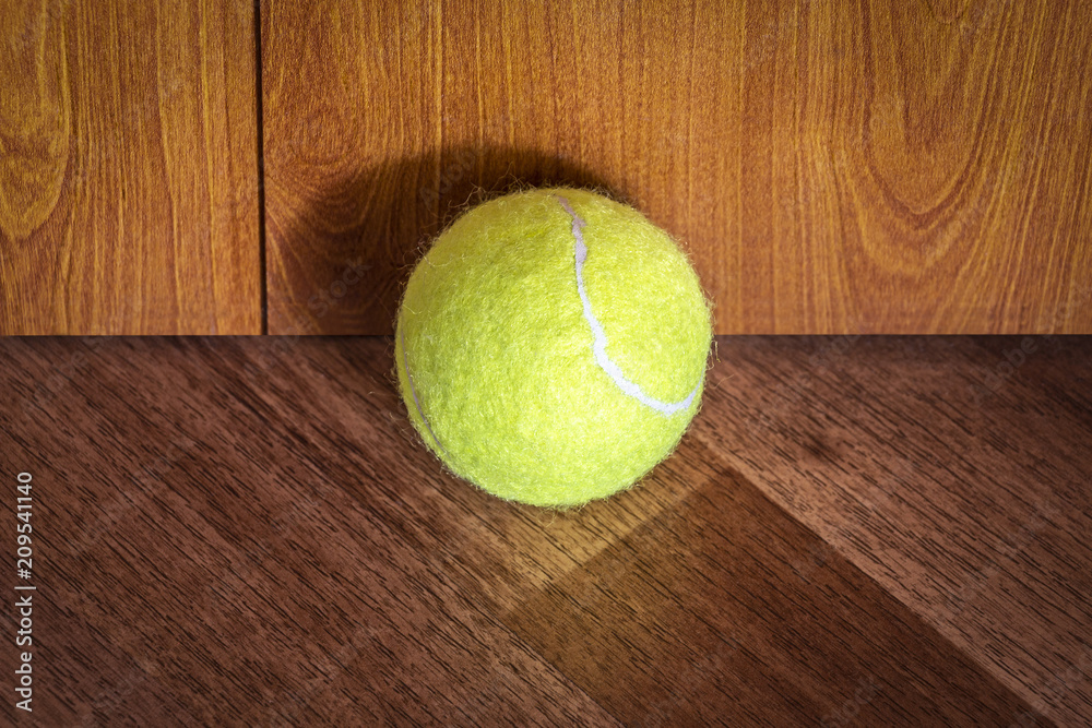 A tennis ball lies in the corner of the room.