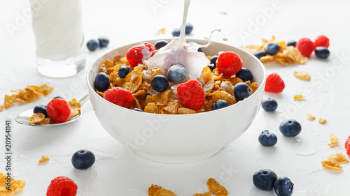 Obraz na płótnie Healthy Morning Breakfast honey Corn flakes with fresh fruits of Raspberry, blueberries and pouring milk in bowl