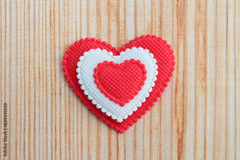 A beautiful red soft heart made of cloth on a light new board. Close-up. Background. A beautiful red soft heart made of cloth on a light new board. Close-up. Background.