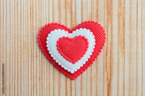 A beautiful red soft heart made of cloth on a light new board. Close-up. Background.