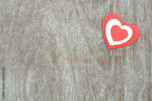 A red soft heart made of cloth pasted onto an old plywood. Background.