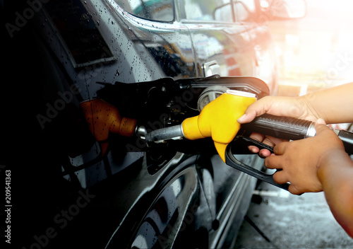 Hand refilling yellow fuel gasoline dispenser the car with fuel at the gasoline station energy crisis
