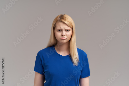 Aggravated brunette female with long straight blonde hair, frowns face in discontent, feels displeasure, being insult by someone
