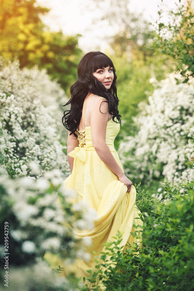 girl in yellow dress is standing between flowering spiraea and sunbeam shines on her. girl in yellow dress is standing between flowering spiraea and sunbeam shines on her.
