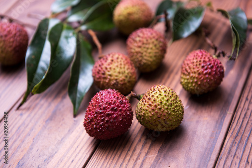 Lychee with leaves on a wooden table.