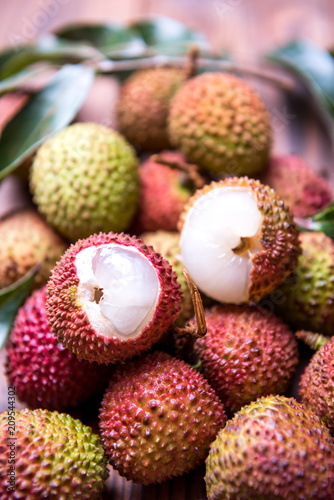 Closeup of fresh lychee with leaves on a wooden table.