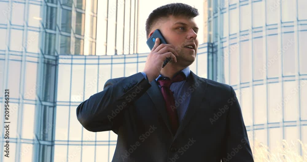 Young handsome businessman talking on phone, in costume, skyscraper Young handsome businessman talking on phone, in costume, skyscraper