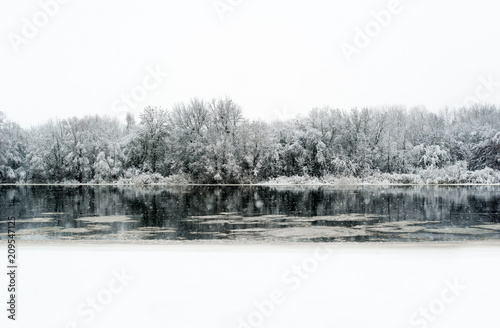 River in winter and tree branches covered with white frost.