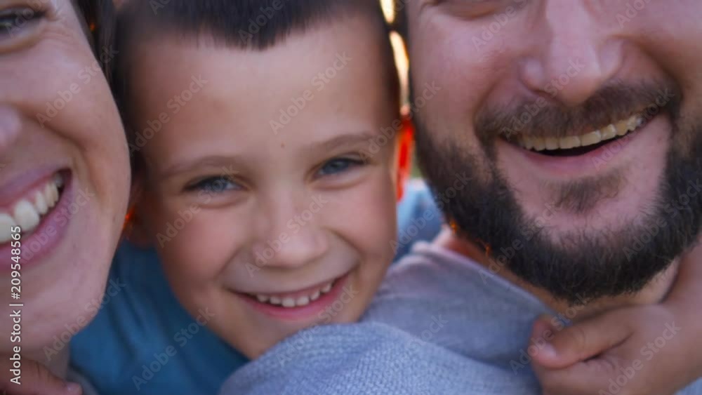 Loving mother and father hugging and kissing son on sunset Loving mother and father hugging and kissing son on sunset