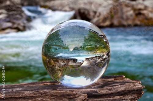 Crystal glass ball sphere reveals waterfall landscape with spherical perspective photo