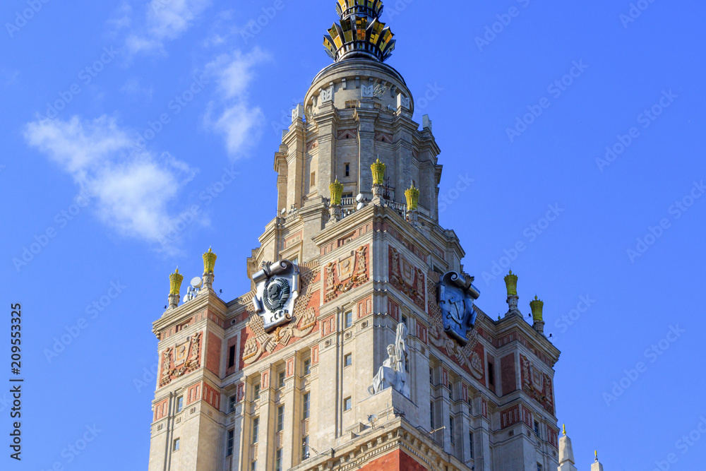 Fragment of Lomonosov Moscow State University (MSU) tower with national emblem of USSR on a blue sky background