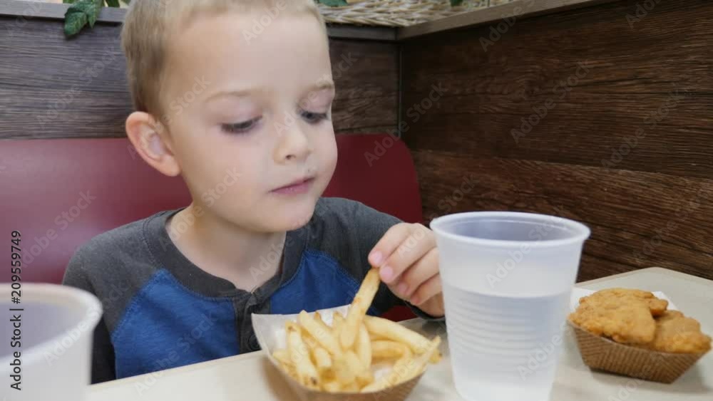 Boy eating his unhealthy french fries in fast food restaurant Boy eating his unhealthy french fries in fast food restaurant