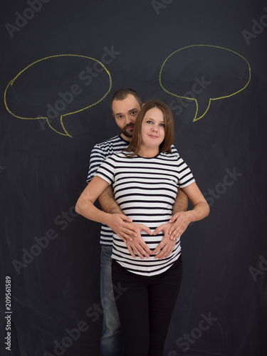 pregnant couple posing against black chalk drawing board