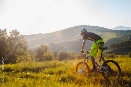 Fototapeta Naklejka Na Ścianę i Meble -  A cyclist on a mountain bike rises uphill. And looks at the scenic landscape.