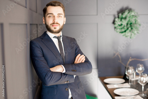 Fotografi Serious confident handsome bearded businessman crossing arms on chest and leanin