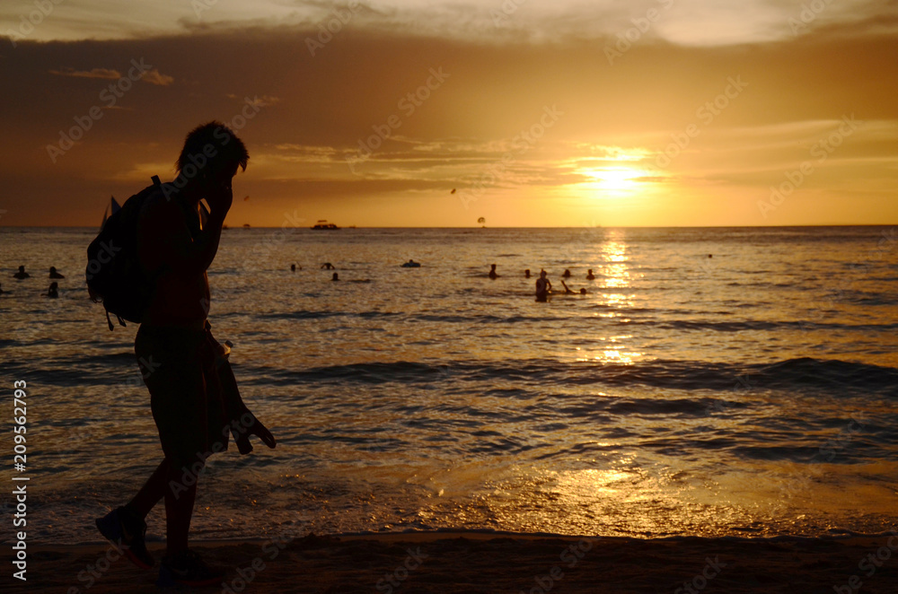 Sunset time at a beautiful island with orange gradient colour of sky and people playing around the beach. Sunset time at a beautiful island with orange gradient colour of sky and people playing around the beach.