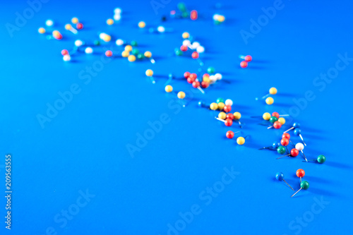 Office supplies in the form of colored buttons and paper clips on blue background.