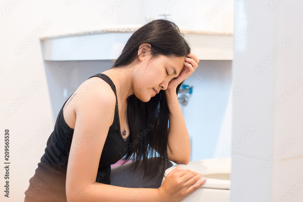 Asian woman with morning sickness,Pregnant female nausea into the toilet bowl Asian woman with morning sickness,Pregnant female nausea into the toilet bowl
