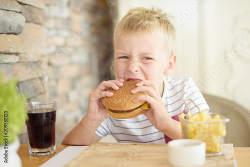 boy eating burger in cafe