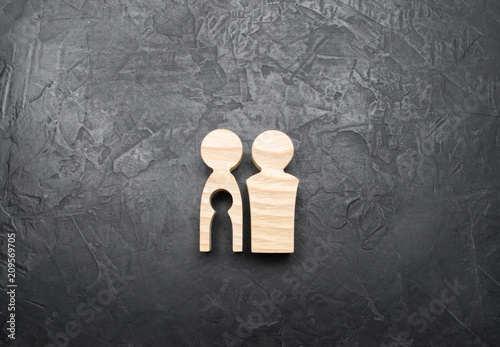 Wooden figurines of parents with a void in the form of a child inside the body of a woman on a concrete gray background. The concept of infertility and the absence of a child, the loss of a child.