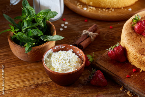 Baking background with strawberry tart covered with whipped sour cream, ingredients over wooden background.