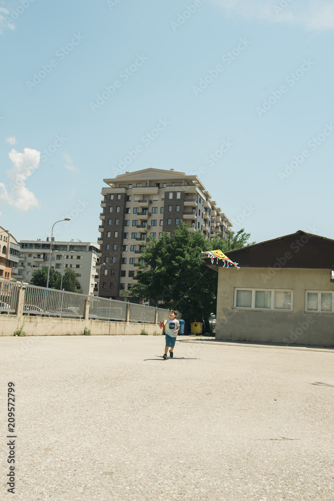 Young boy playing with kite in the school yard on a sunny day
