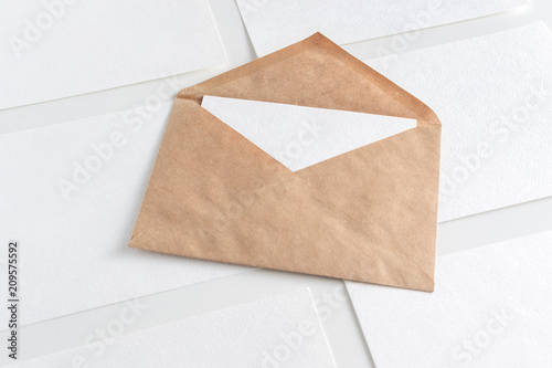 Mockup of horizontal business cards stacks arranged in rows and brown envelope in center at white textured background.