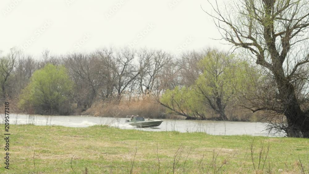 Fisherman on motor boat sailing on water on background trees on river shore Fisherman on motor boat sailing on water on background trees on river shore