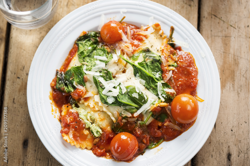Spinach and ricotta ravioli in tomato sauce with cherry tomatoes, pecorino cheese and pine kernels Spinach and ricotta ravioli in tomato sauce with cherry tomatoes, pecorino cheese and pine kernels