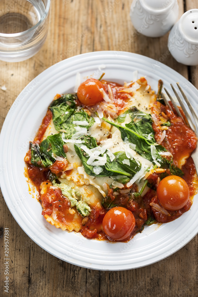 Spinach and ricotta ravioli in tomato sauce with cherry tomatoes, pecorino cheese and pine kernels