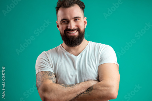 Confident serious man standing with arms crossed against black background at studio photo