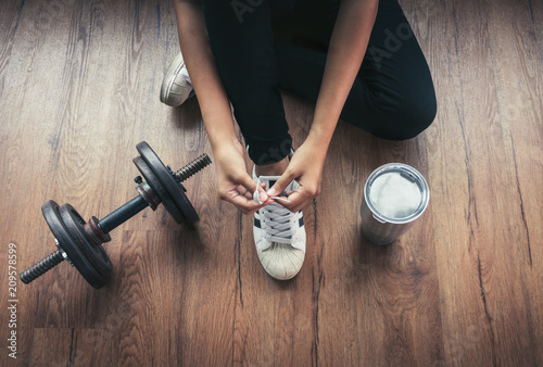 woman tying shoe laces in gym, top view