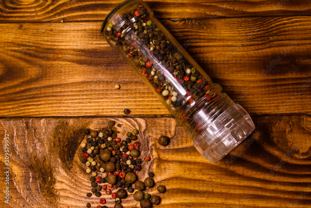 Pepper mill and scattered spices on the wooden table. Top view