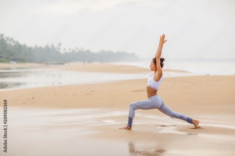 Caucasian woman practicing yoga at seashore of tropic ocean Caucasian woman practicing yoga at seashore of tropic ocean