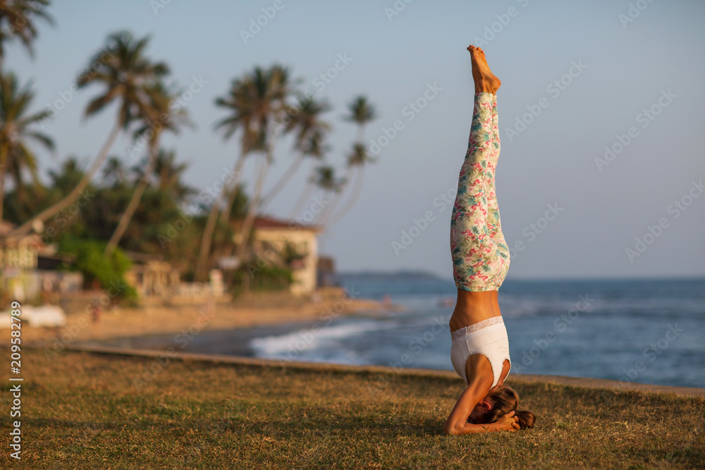 Caucasian woman practicing yoga at seashore of tropic ocean Caucasian woman practicing yoga at seashore of tropic ocean
