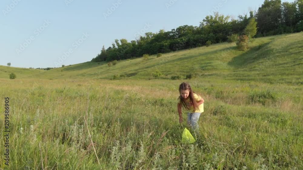 little girl is catching butterflies with a net in the grass