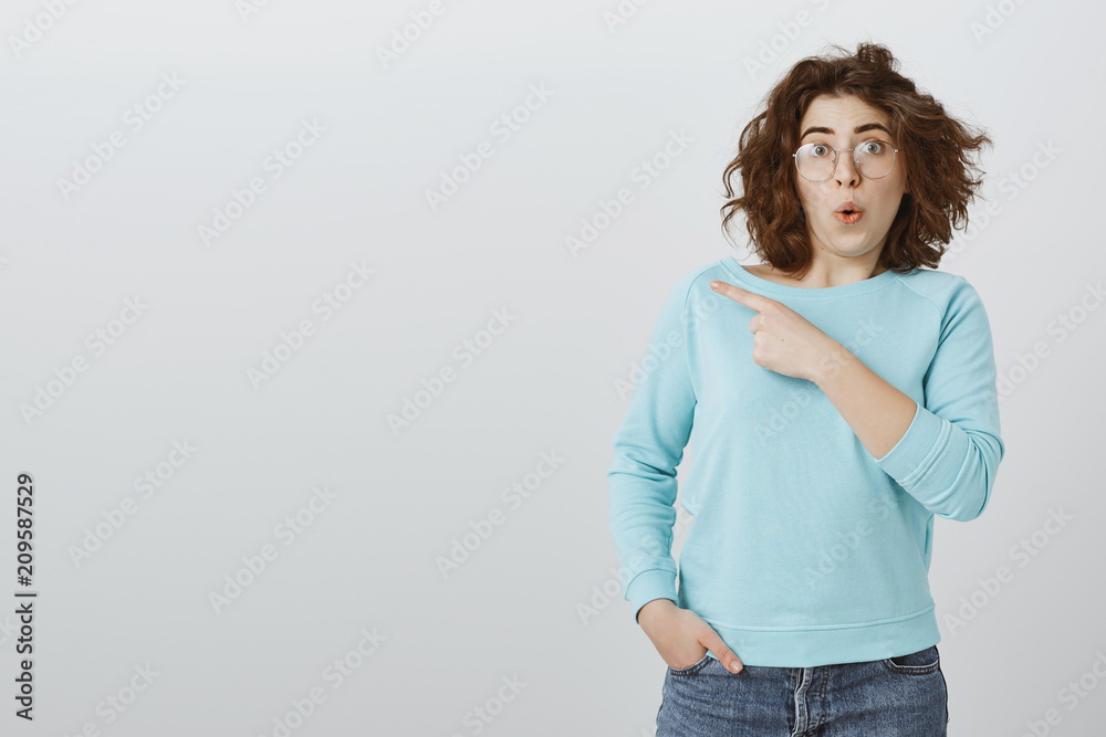 Wow, can you imagine superstar standing in that direction. Portrait of amazed good-looking woman with trendy haircut and glasses, being impressed and curious, pointing at upper left corner, fascinated Wow, can you imagine superstar standing in that direction. Portrait of amazed good-looking woman with trendy haircut and glasses, being impressed and curious, pointing at upper left corner, fascinated