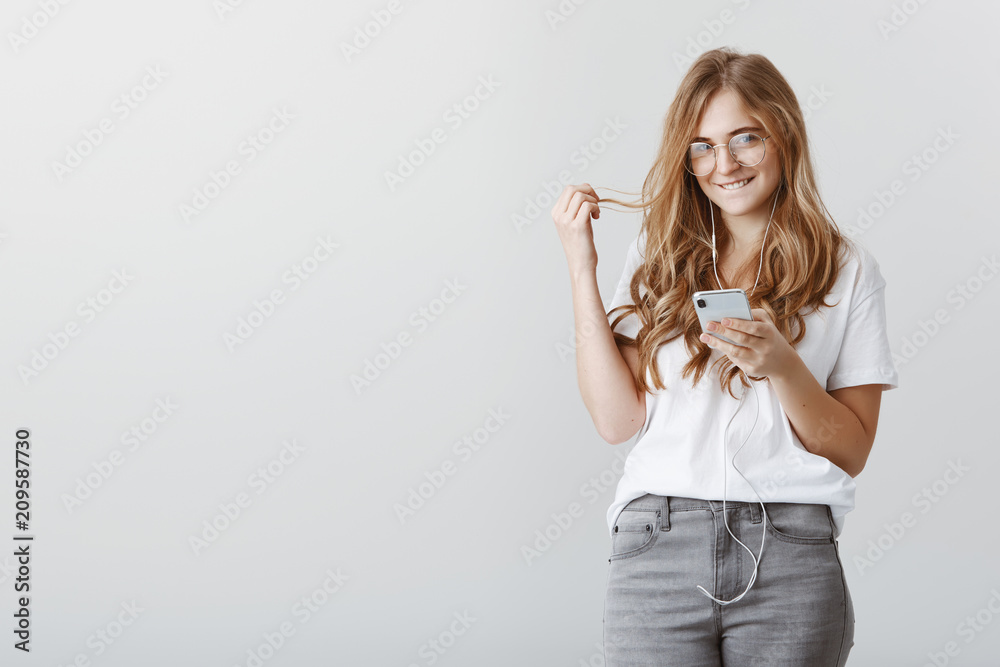 Having nasty ideas in mind. Portrait of beautiful charming blonde student in glasses, holding smartphone, biting lip and playing with hair, smiling curiously, flirting or being in romantic mood Having nasty ideas in mind. Portrait of beautiful charming blonde student in glasses, holding smartphone, biting lip and playing with hair, smiling curiously, flirting or being in romantic mood