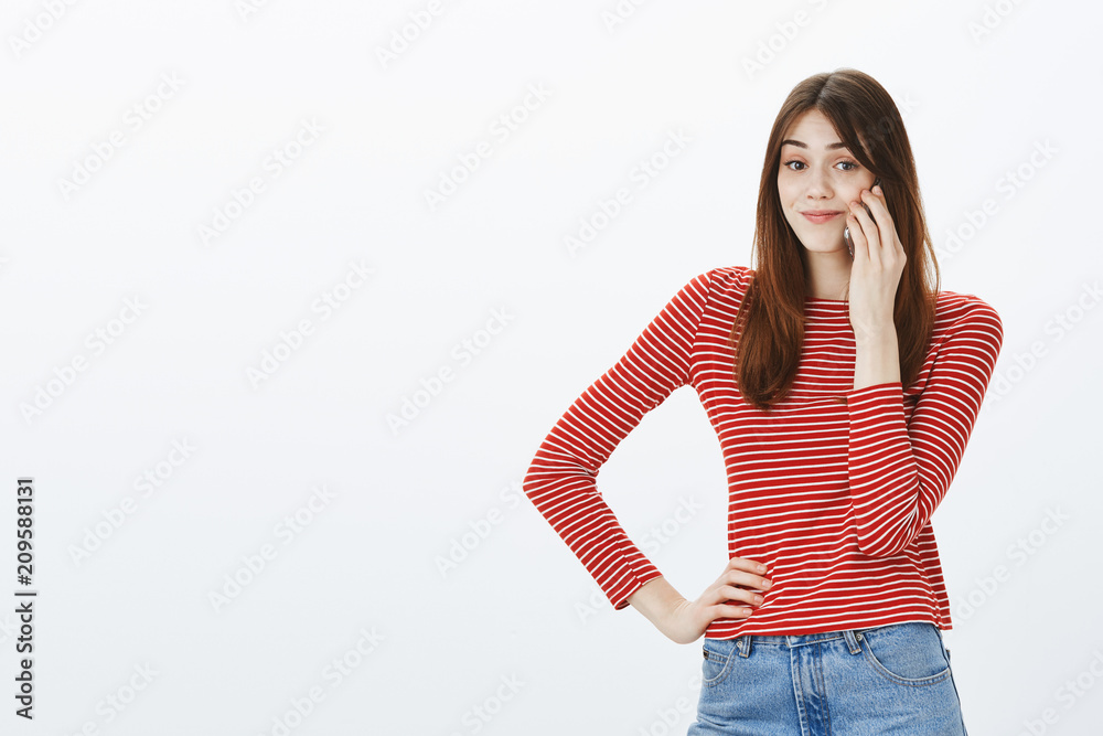 Girl calling friend who late for meeting. Sarcastic attractive female coworker, holding hand on hip and smartphone near ear, smirking with annoyance, looking at camera with bothered expression Girl calling friend who late for meeting. Sarcastic attractive female coworker, holding hand on hip and smartphone near ear, smirking with annoyance, looking at camera with bothered expression