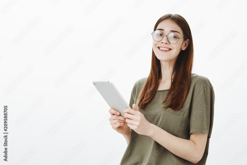 Beautiful site editor checking schedule during worktime. Indoor shot of good-looking creative female freelancer in stylish eyewear, holding digital tablet and smiling broadly, browsing in network Beautiful site editor checking schedule during worktime. Indoor shot of good-looking creative female freelancer in stylish eyewear, holding digital tablet and smiling broadly, browsing in network