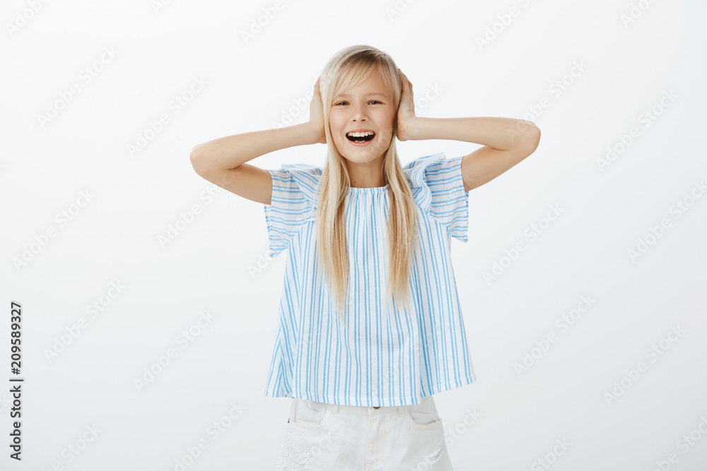 Studio shot of disobedient child with bad behaviour standing over gray background, covering ears with palms and whining, complaining and rejecting listening to parents, standing over gray wall Studio shot of disobedient child with bad behaviour standing over gray background, covering ears with palms and whining, complaining and rejecting listening to parents, standing over gray wall
