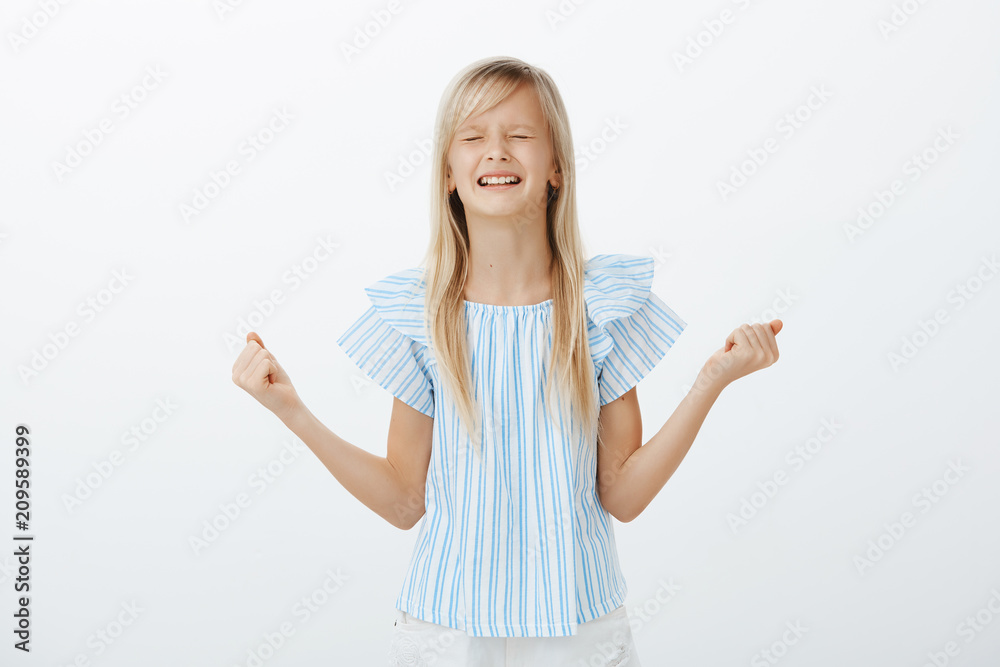 Offended little girl whining and crying, being disobedient. Displeased upset young daughter with blond hair, clenching spread fists and teeth, arguing wanting candy, standing over gray wall Offended little girl whining and crying, being disobedient. Displeased upset young daughter with blond hair, clenching spread fists and teeth, arguing wanting candy, standing over gray wall