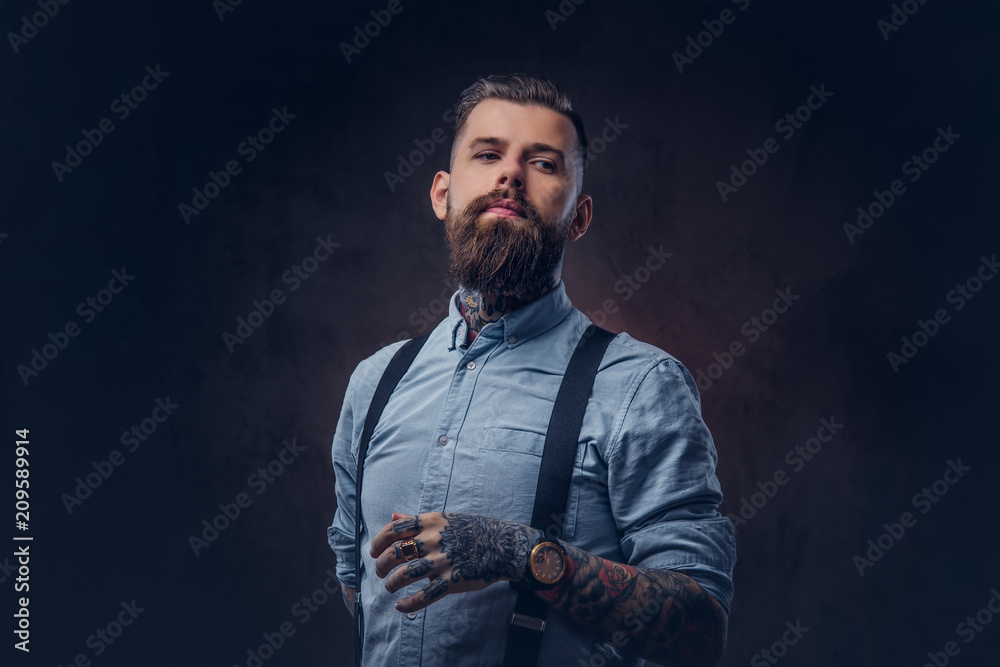 Portrait of a handsome old-fashioned hipster in a blue shirt and suspenders.