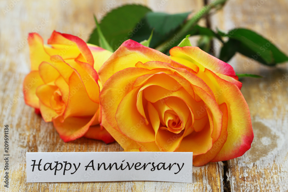 Happy Anniversary card with two orange roses on rustic wooden surface